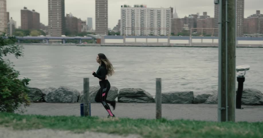 A woman is jogging by the water
