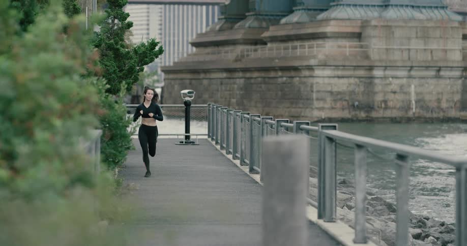 A woman runs along the sidewalk next to the water