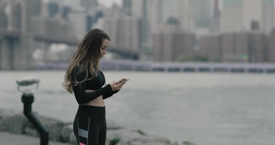 Young woman texting with her smartphone near the river