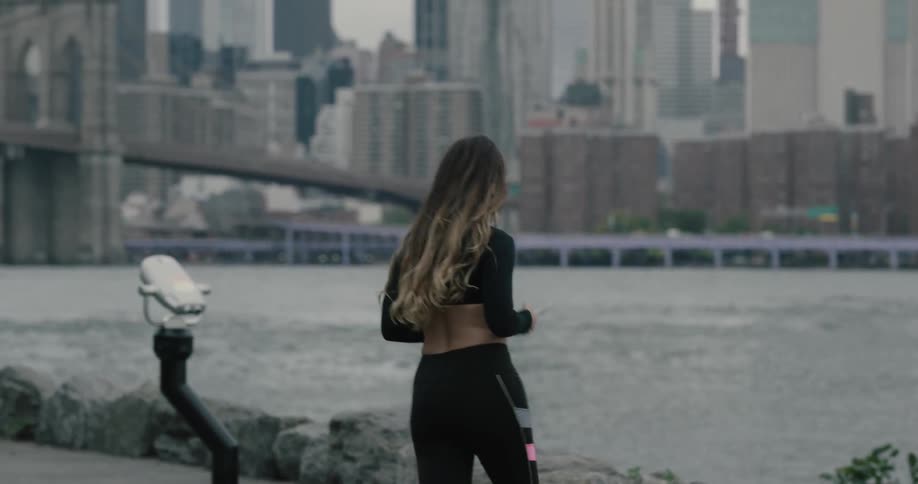 A woman is texting and then jogging near a downtown city