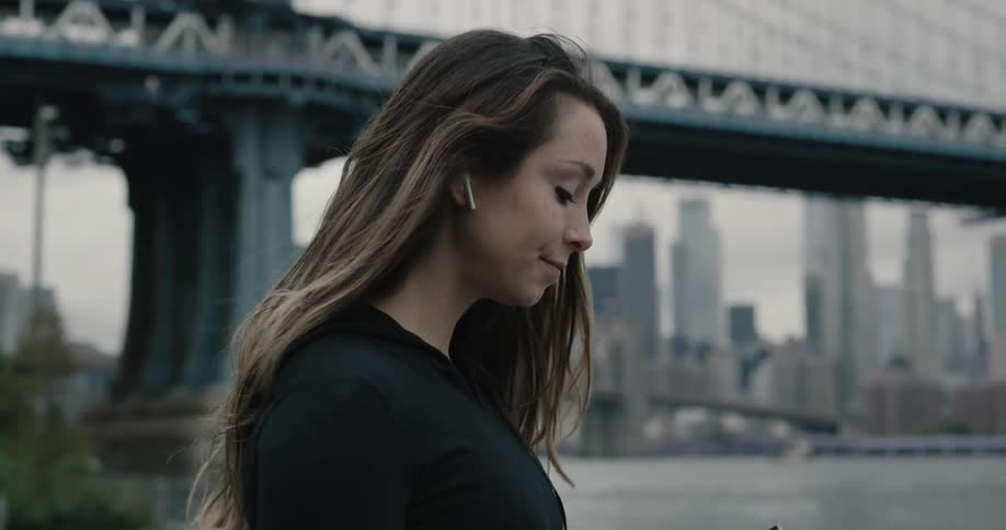 Woman jogs near the river then stops to look at her cellphone