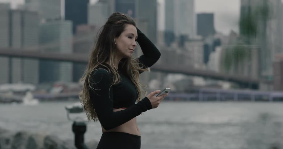 A woman is checking her phone on a windy day