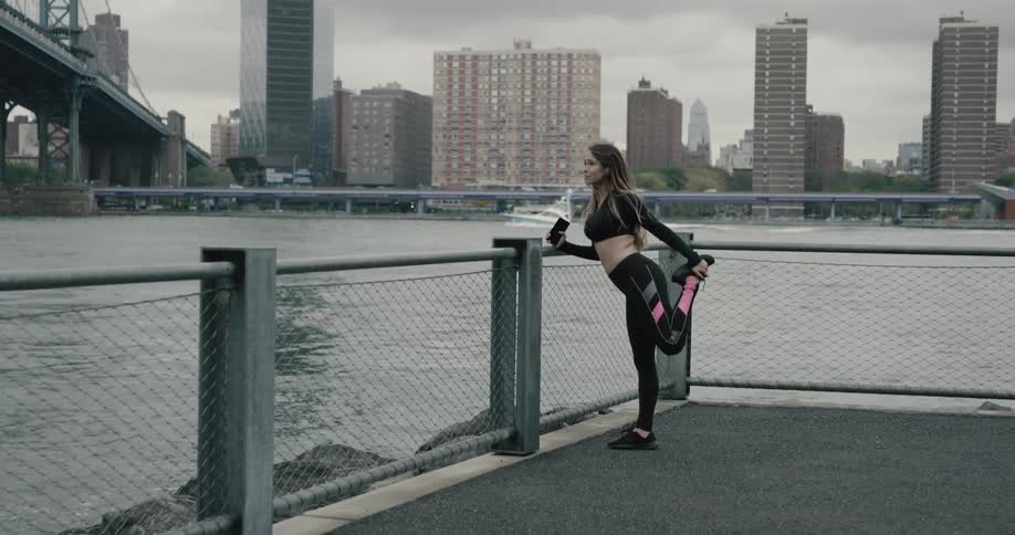 A woman runs over to the railing to stretch by the water