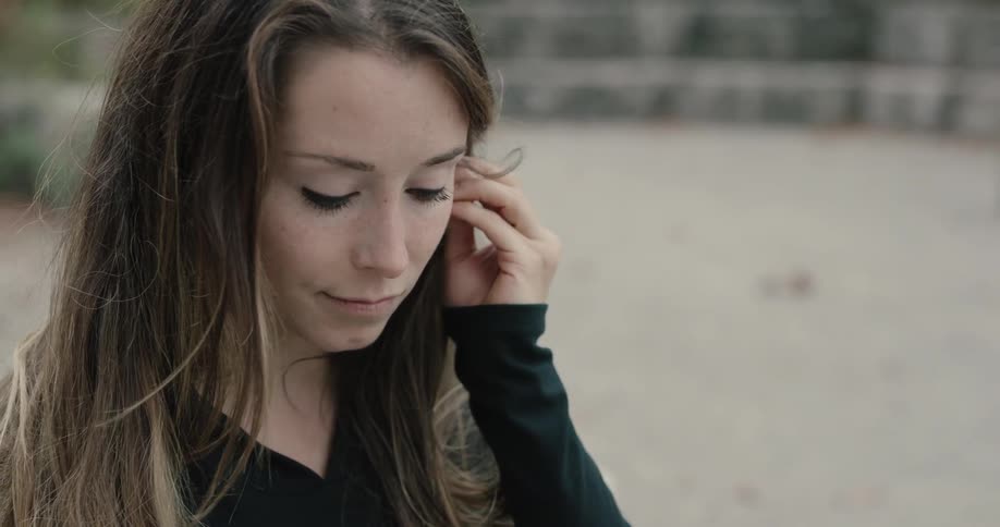 Woman wearing bluetooth earphones uses smartphone during daylight