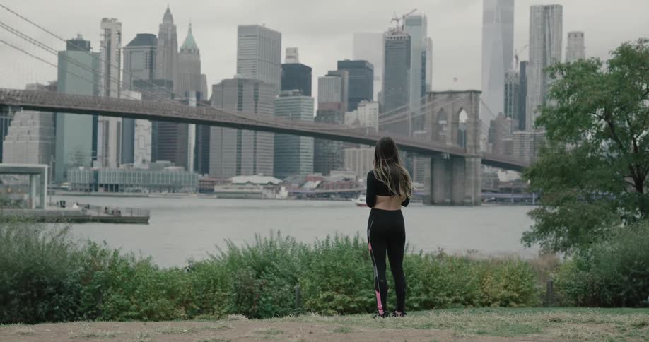 Male with sport apparel staring at the bridge on the riverbank