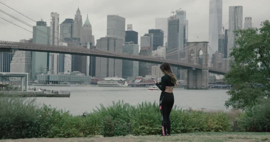 Young woman play with her phone near the river