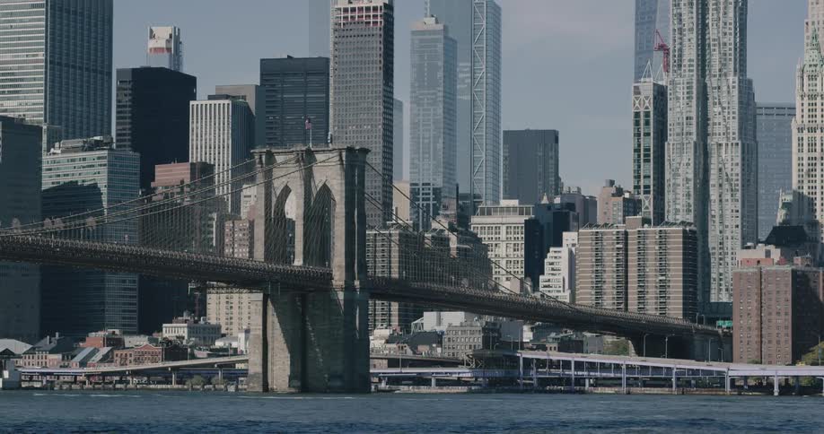 A still view of a bridge in front of a busy urban town center on a clear day