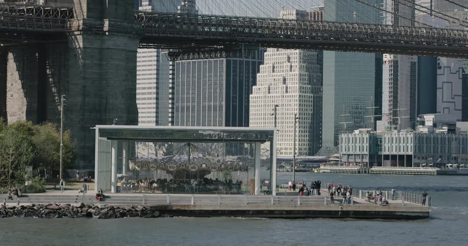 People walk around near merry go round and waterfront