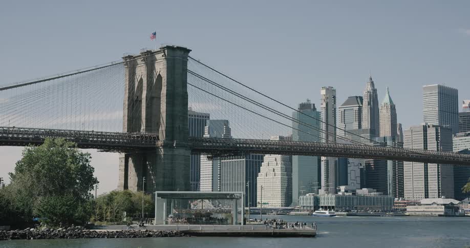 A stage set up in a park across the river from new york city by the brooklyn bridge