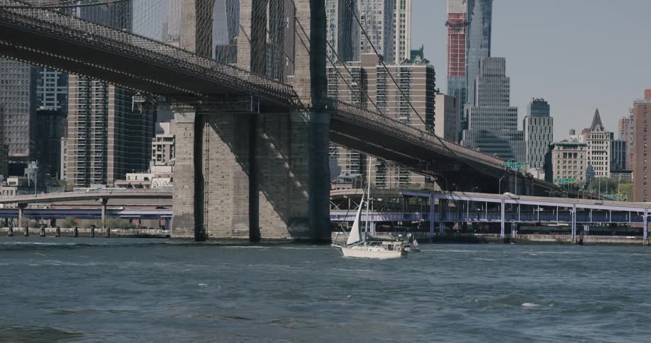 A boat sails through the water under a bridge in a city