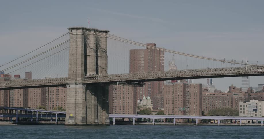 A large suspension bridge over a river surrounded by buildings