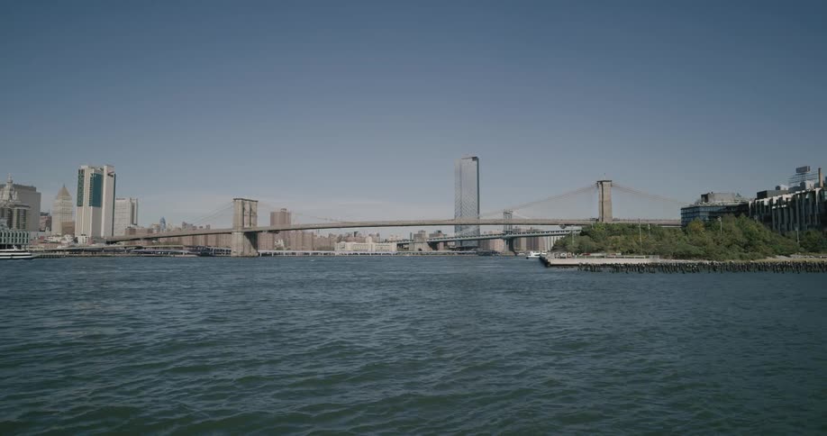 Water ripples on a river flowing beneath a large city bridge in the daytime