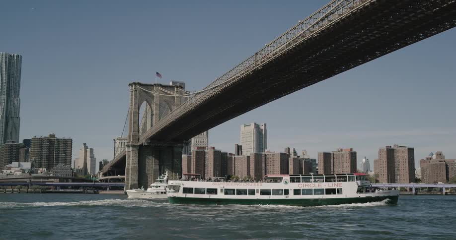A passenger boat floats under a bridge