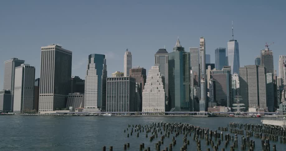 Rows of wood mooring posts near shoreline with downtown skyscrapers in background