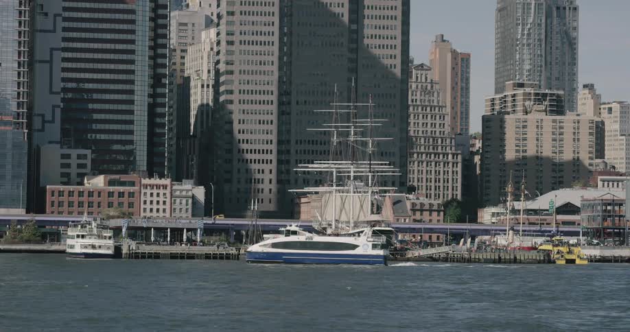A boat travels on a calm body of water next to a metropolis