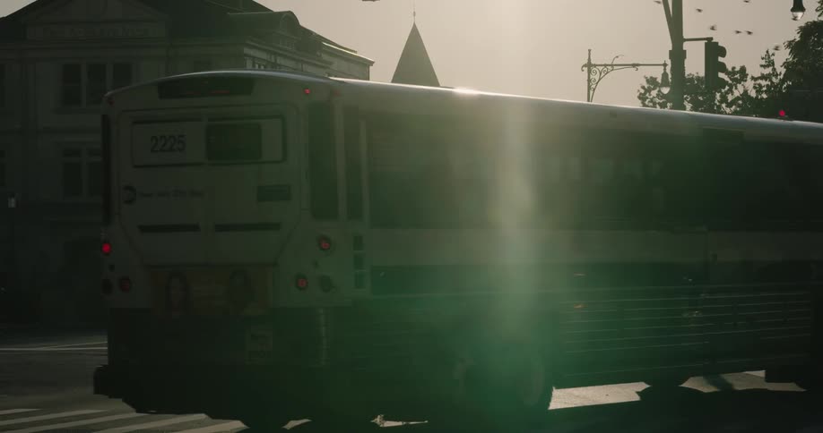 A bus and cars go through a traffic light at an intersection
