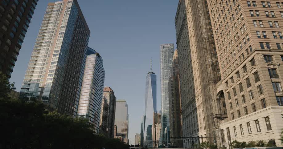 A very tall skyscraper with an antenna on top towers above many other buildings in an urban city area