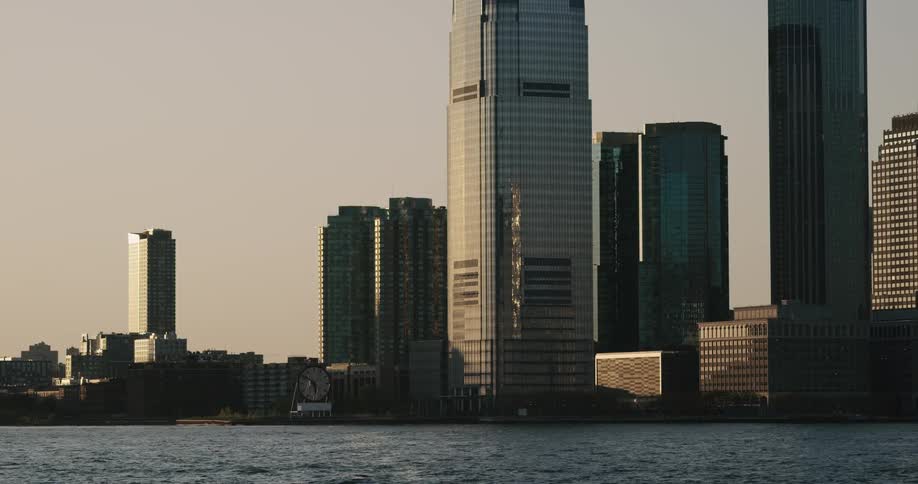 Large sky scrapers built next to a body of water reach towards the sky
