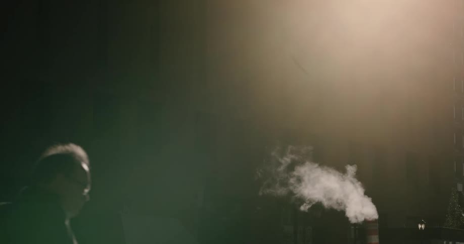 Smoke billows out of stacks as people walk along