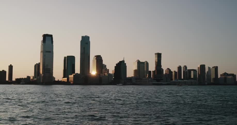 Skyline of the city with tall buildings next to the sea at sunset