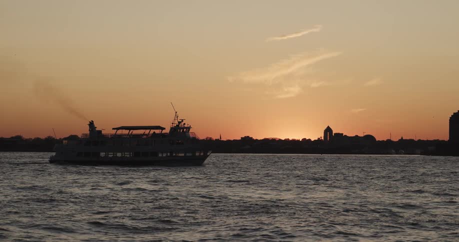 A silhouetted boat floats on a body of water at sunset