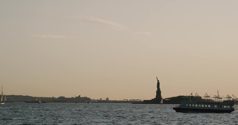 Landscape view of a boat crossing in front of the statue of liberty