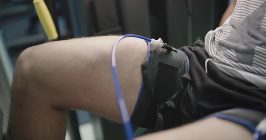 A physical therapist attaches tubes to a mans thighs