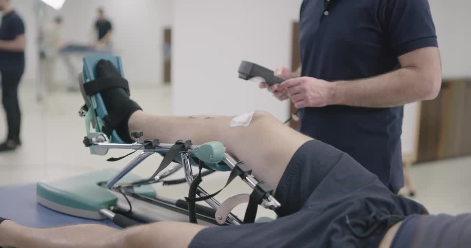 A man has his leg on a motorized table while a therapist does testing