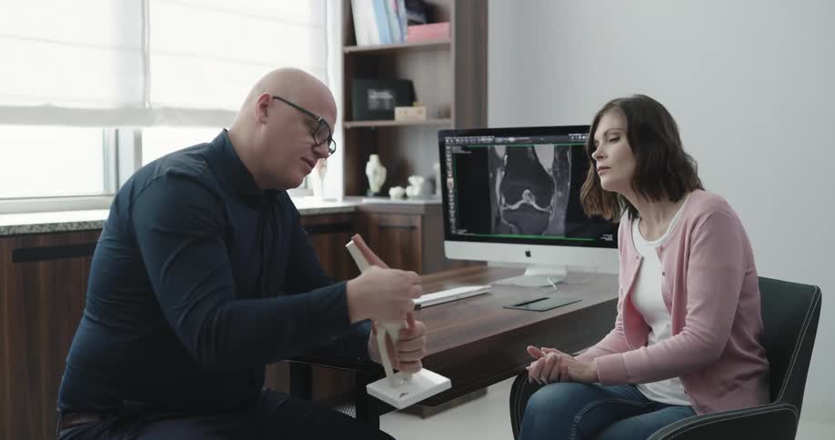 A man is explaining a model of a knee joint to a woman