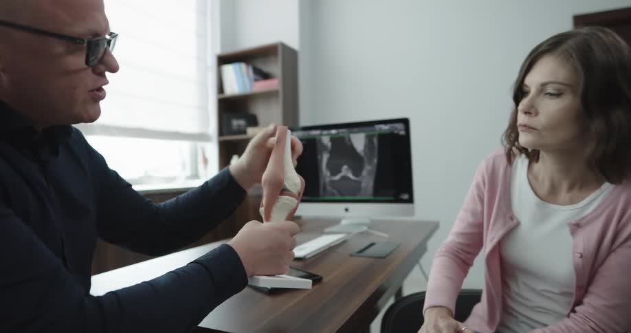 A doctor and patient discuss a knee injury in a doctors office
