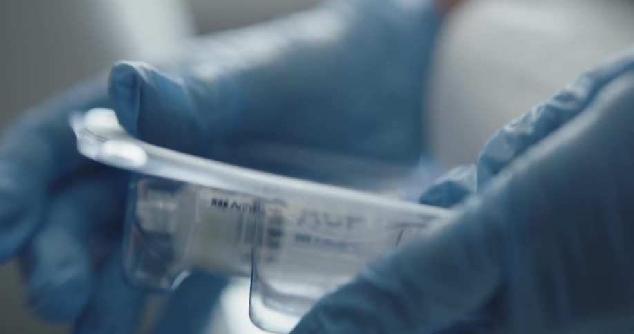 Pair of blue gloves removing an injection from a sterile package