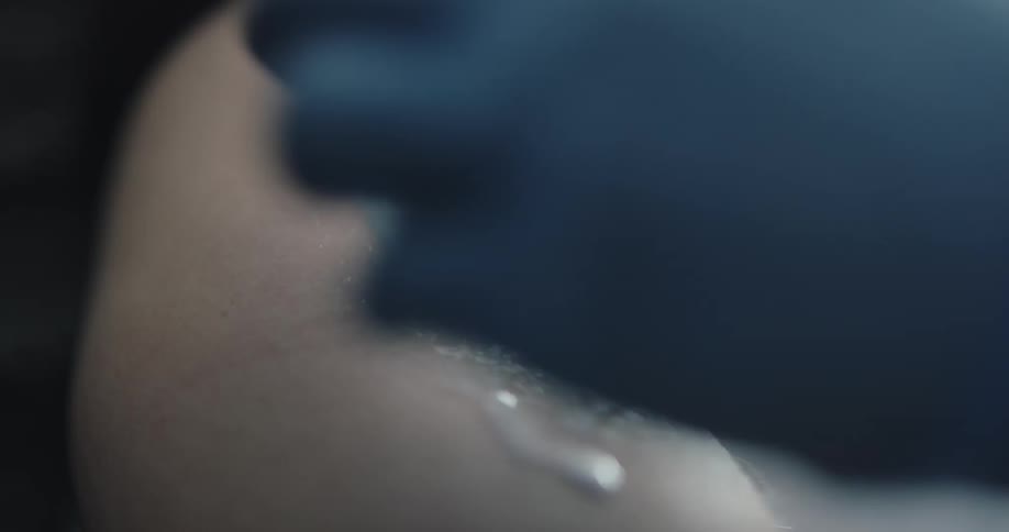 Person in medical gloves sprays liquid on inner elbow then wipes liquid