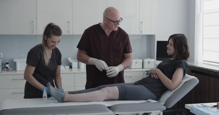 A male and female nurse applying medication to a female patients leg