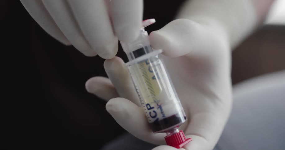 Pair of white gloves handing a syringe to pair of blue gloves
