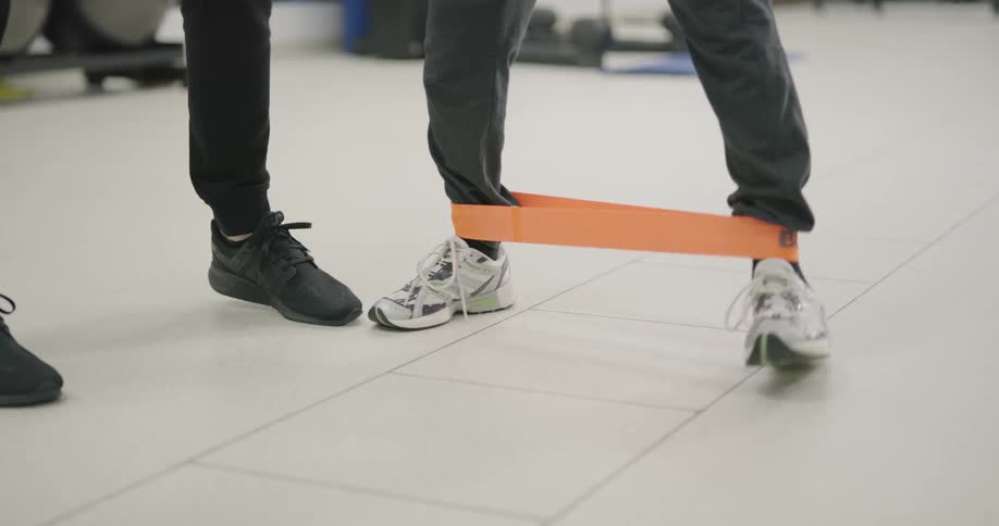 A male exercises with a band around his ankles
