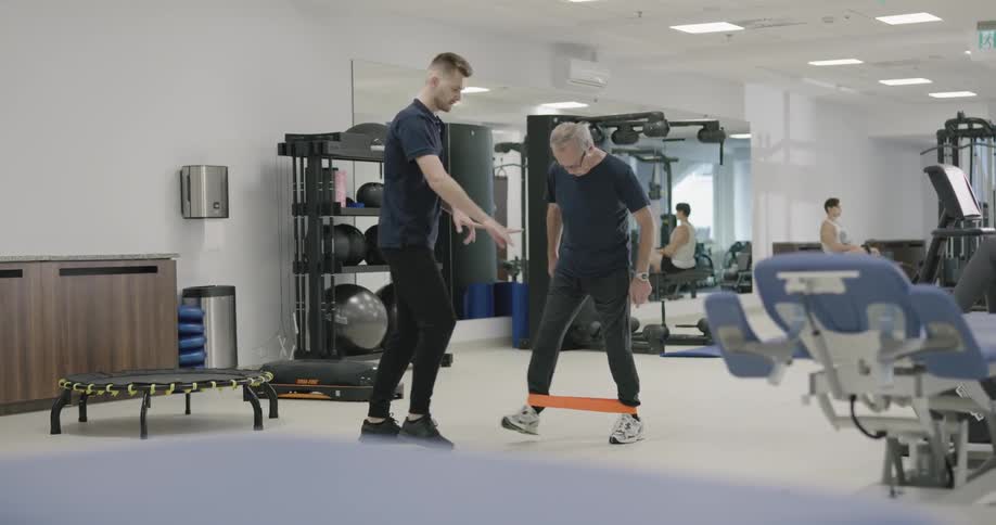 A physical therapist works with a man in a gym