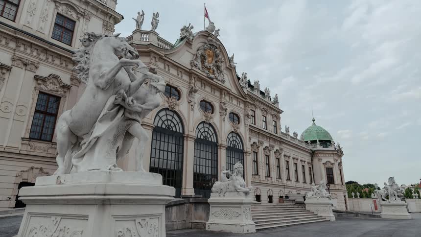 Clouds in the sky pass over an ornate landmark building adorned with numerous sculptures and built with remarkable architecture