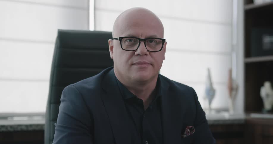 A man is sitting in a black chair in his office