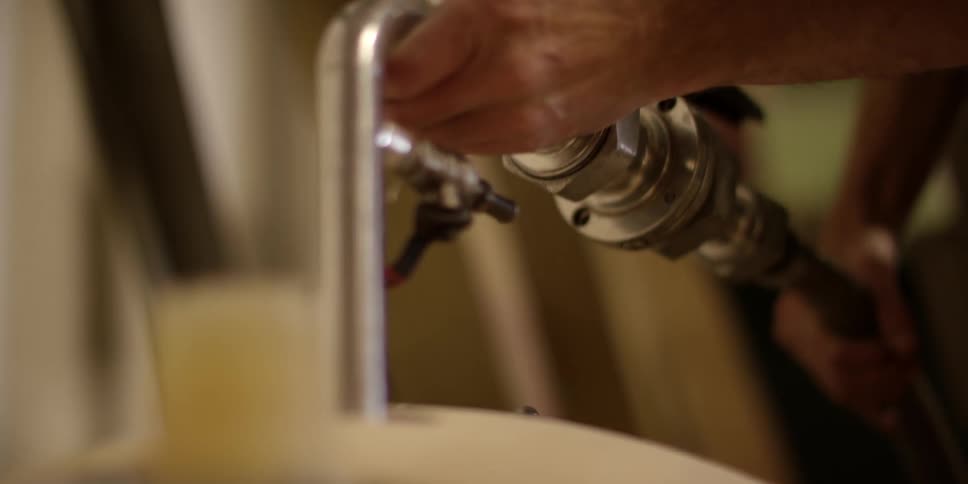 A man sliding a pipe into a vat