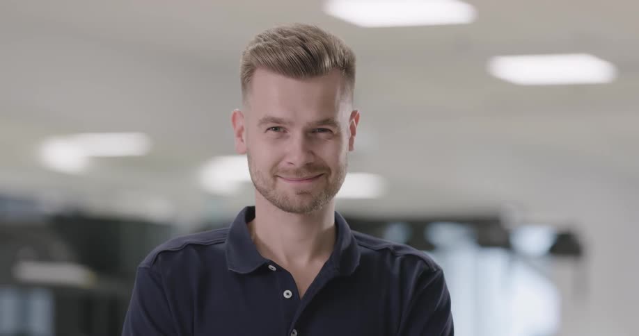 A man is smiling and standing indoors