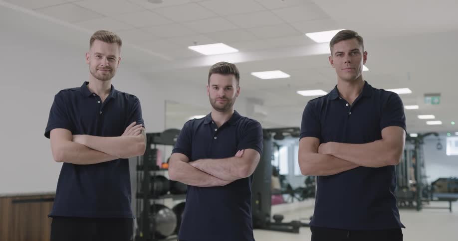 Male fitness trainers posing with arms crossed at the gym