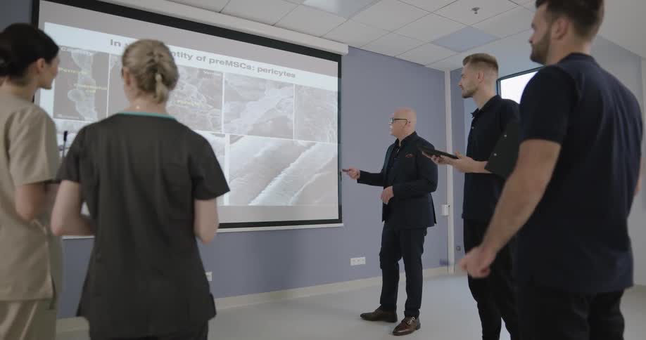 A group watches a presentation in front of a screen