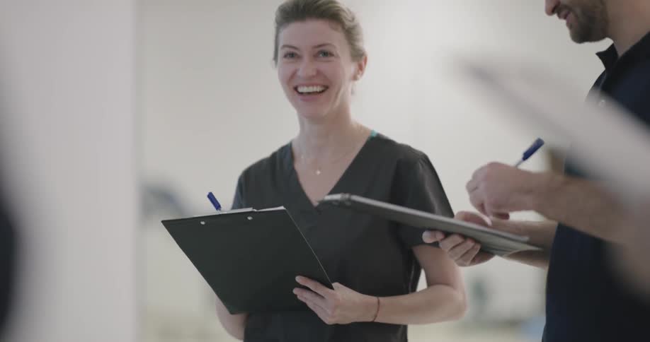 A group of people holding clipboards laugh while having a discussion