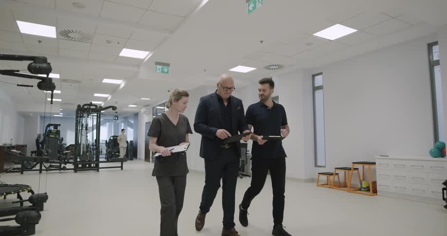 Three people walk together in the gym talking
