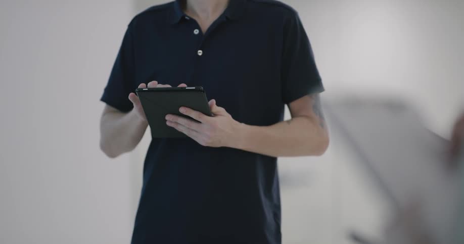A man uses a black tablet in an all white room