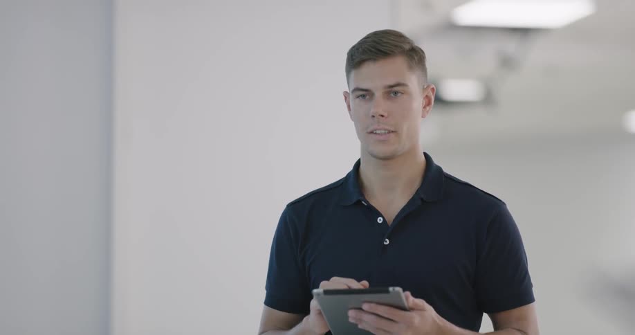 A man gestures and talks to people while using a tablet in his hands