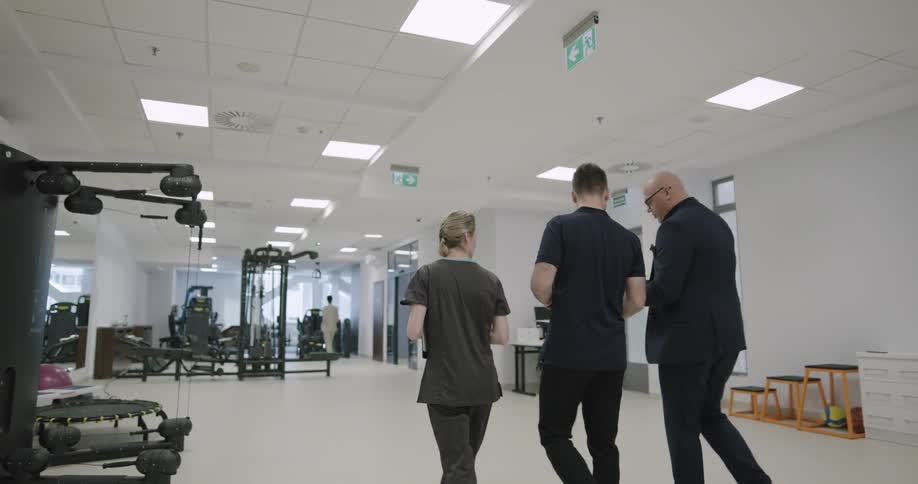 Three people walk into a rehab exercise room