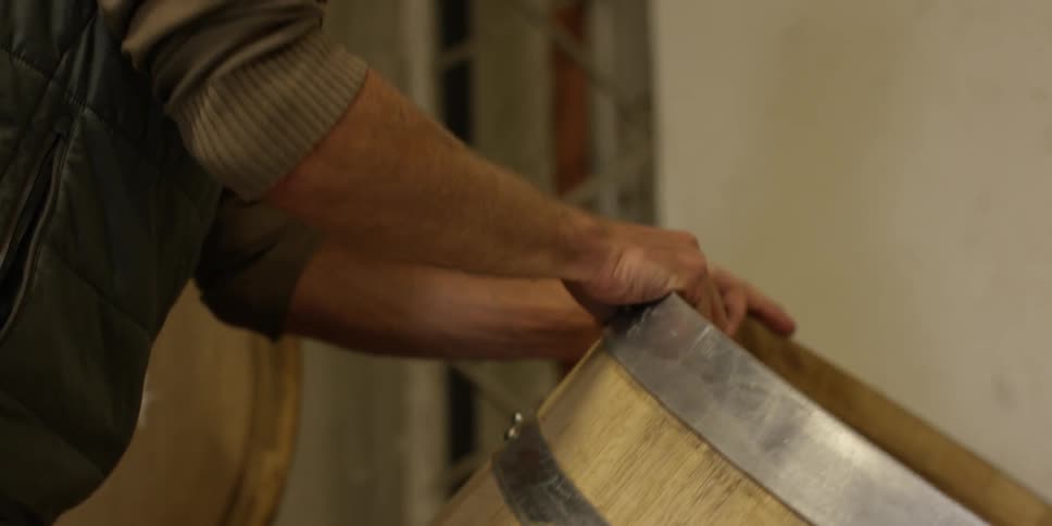 A man moves a wooden barrel