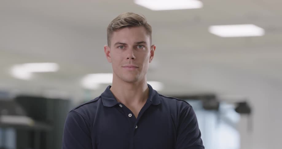 A man is standing indoors and smiling