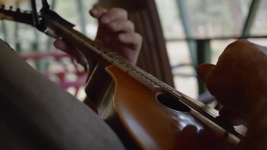 A person strums the strings of a ukulele